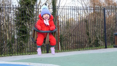 Küçük kız parkta salıncakta eğleniyor.