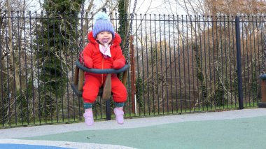 Küçük kız parkta salıncakta eğleniyor.