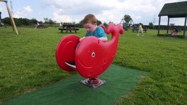 Mavi tişörtlü kızıl saçlı çocuk güneşli bir günde Playpark 'ta eğleniyor.