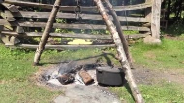 Old woman cooking bread on a griddle over a fire outdoors at The Ulster America Folk Park in Northern Ireland 
