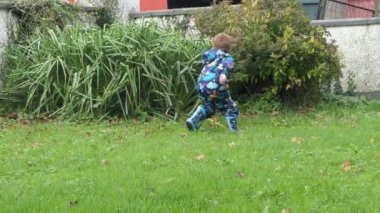 Red headed boy lifting palm leaves in a garden