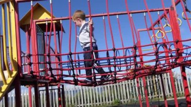Red headed boy playing on the rope bridge at a playpark