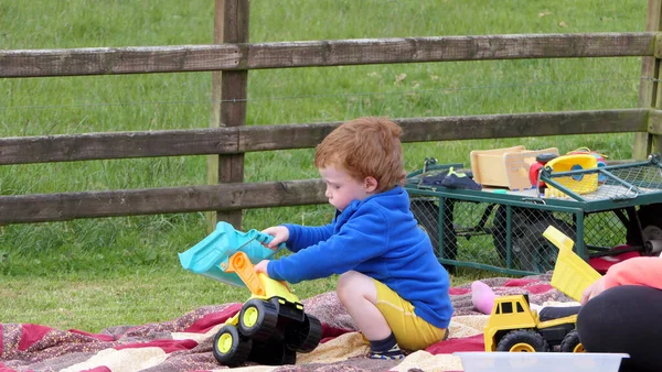 红头发男孩在花园里的草坪上玩野餐毯 — 图库照片
