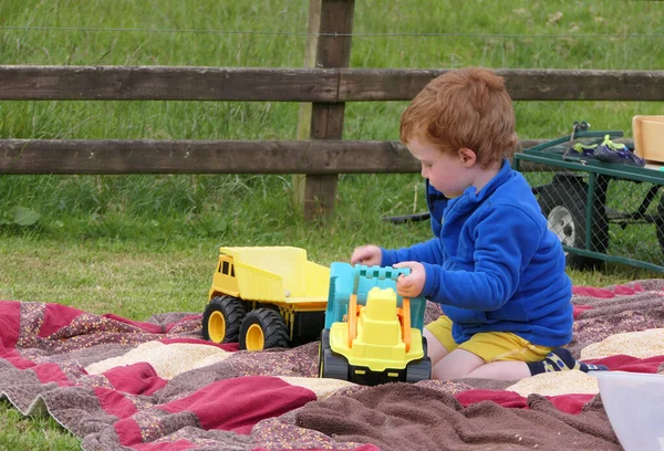 红头发男孩在花园里的草坪上玩野餐毯 — 图库照片