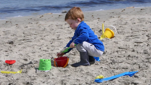 Рыжий Мальчик Играет Ведром Лопаты Диггер Песчаном Пляже — стоковое фото