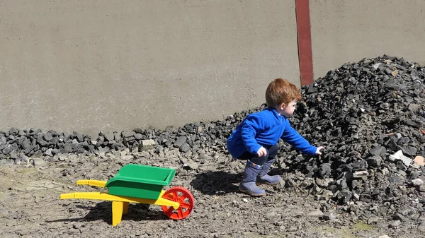 Rudy Chłopiec Bawiący Się Kamieniami Taczką Dla Dzieci — Zdjęcie stockowe