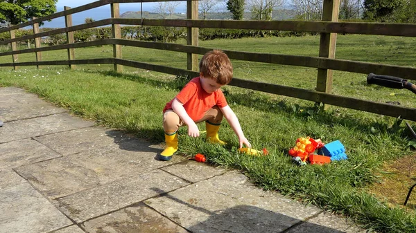 Red Headed Boy Having Fun Playing His Toys Garden — Zdjęcie stockowe