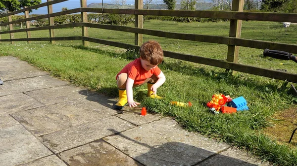 Red Headed Boy Having Fun Playing His Toys Garden — Zdjęcie stockowe