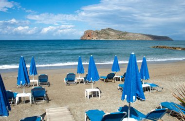 Girit adası, Yunanistan Agia Marina Sahili Chania Şemsiyeleri ve ufuktaki kumların üzerinde güneşlenen Rocky çıkıntıları