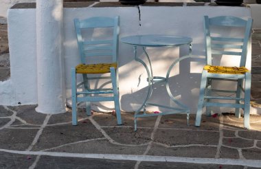 Güzel Folegandros Adası, Yunanistan. Köy meydanında geleneksel taverna masaları ve sandalyeler. Tipik Yunan sahnesi. Peyzaj görünümü.