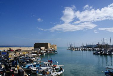 Heraklion, Girit - Yunanistan - 15 Ekim 2010: Limanı koruyan eski kale manzaralı tarihi Venedik limanı. Rıhtıma demirlemiş renkli küçük balıkçı tekneleri. Kopya alanı ile manzara görünümü.