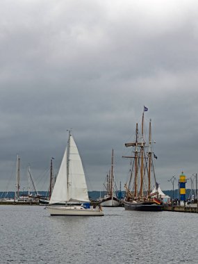Almanya 'nın kuzeyinde Schleswig-Holstein eyâletinde, bulutlu gökyüzü altında Eckernfotte limanında yelkenli gemileri ve deniz fenerleri