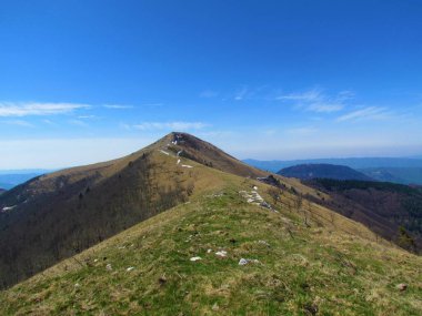 Cerkno, Gorenjska, Slovenya tepelerindeki Porezen Dağı 'na uzanan dağ sıraları, yamaçları kaplayan kuru ot ve ormanlarla kaplı.