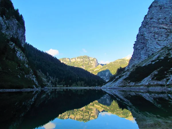 View of Krn lake in Triglav national park and Julian alps, Slovenia before dusk with the mountain Velika Baba in the back lit by sunshine and the reflection of Velika Baba visible in the lake