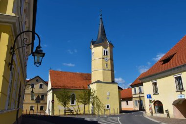 Slovenya 'nın Dolenjska kentindeki Kostanjevica na Krki' de sarı cepheli katolik kilisesi manzarası