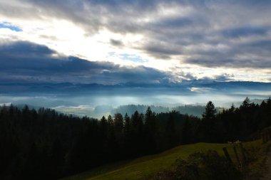 Slovenya 'nın Gorenjska kentinde güneş ışığıyla aydınlatılan sisle kaplı manzaranın görüntüsü