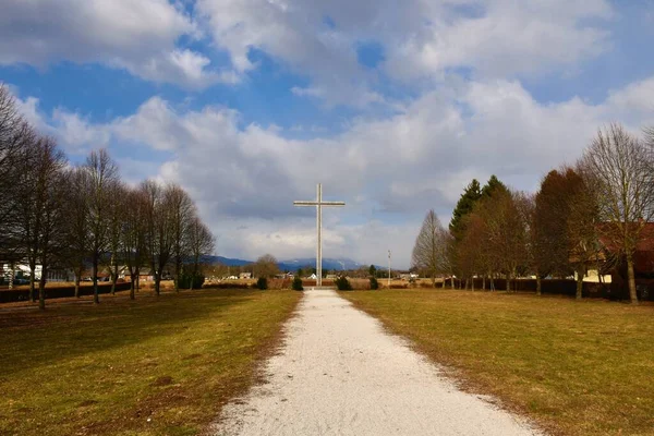 Large metal cross at the and of a gravel path in Brezje, Gorenjska, Slovenia