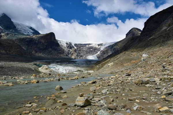 River flowing from Pasterze Glacier in Glockner Group in High Tauern in Austrian Central Alps, Carinthia, Austria and mountain covered in clouds
