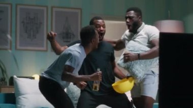 Afro-Amerikalı hayranlar oturma odasında tezahürat yapıyorlar.