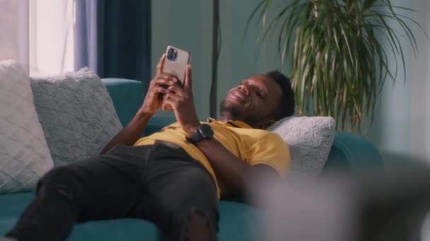 Позитивный чёрный мужчина просматривает социальные сети — стоковое видео