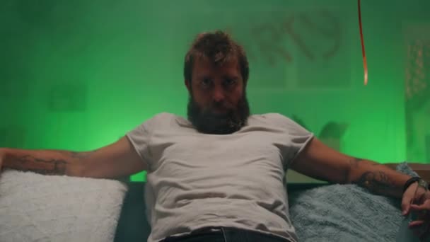 Vousatý muž s alkoholem sedící na pohovce — Stock video