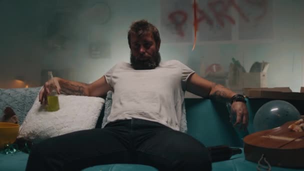 Uomo che beve alcol sul divano in camera fumosa — Video Stock