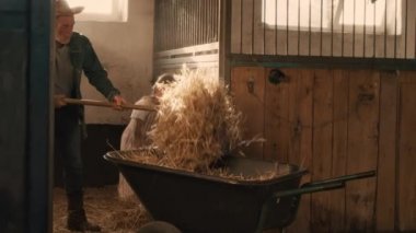 Büyükbaba ve torun el arabasına saman yüklüyorlar.