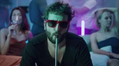 Kız arkadaşlarının yanında nargile içen adam.