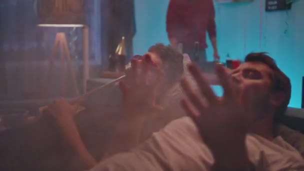 Мужчина курит рядом с другом во время вечеринки — стоковое видео