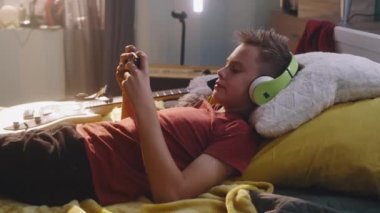 Genç müzisyen cep telefonundan video izliyor.