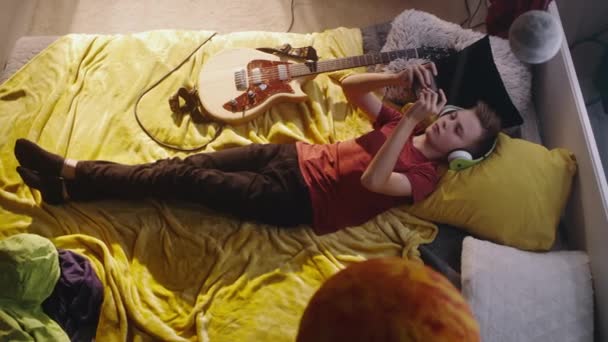 Guitarrista adolescente usando smartphone en la cama — Vídeo de stock