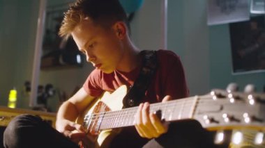 Genç rockçı yatak odasındaki prova sırasında gitar çalıyor.