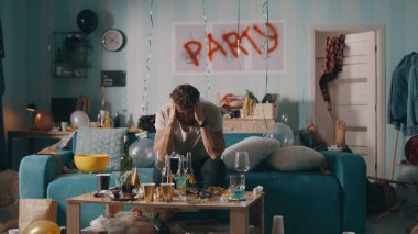 Akşamdan kalma adam kanepede oturuyor.