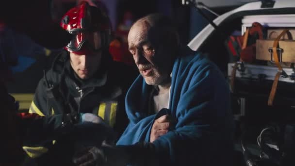 Starszy ocalały rozmawia z pracownikami służby ratunkowej. — Wideo stockowe