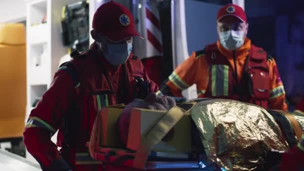 Paramédicos hablando y cargando al hombre inconsciente en la furgoneta — Vídeos de Stock