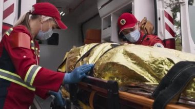 Sağlık görevlileri adamı araca yüklüyor.