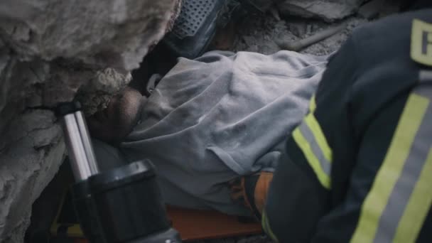 Рятувальники тягнуть людину з купи щебеню — стокове відео
