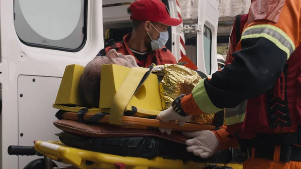 Paramédicos carregando homem no veículo — Fotografia de Stock