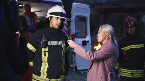 Female reporter interviewing rescuer in evening — Stock Photo, Image