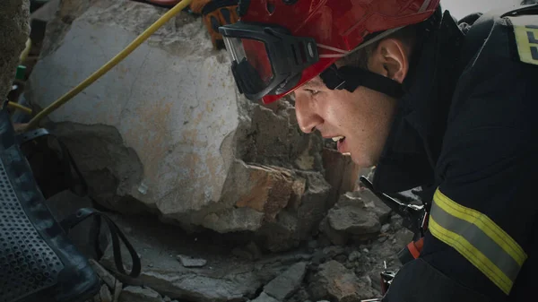 Male rescuer examining rubble and talking — Stock Photo, Image