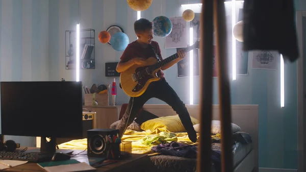 Adolescente tocando la guitarra en el dormitorio — Foto de Stock