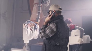 Atölyede zanaatkar akıllı telefondan konuşuyor.