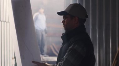 Hangarda polimer bloğu inceleyen bir zanaatkar.