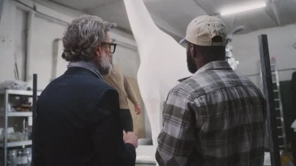 Diverse mannen bespreken giraffe standbeeld productie — Stockvideo