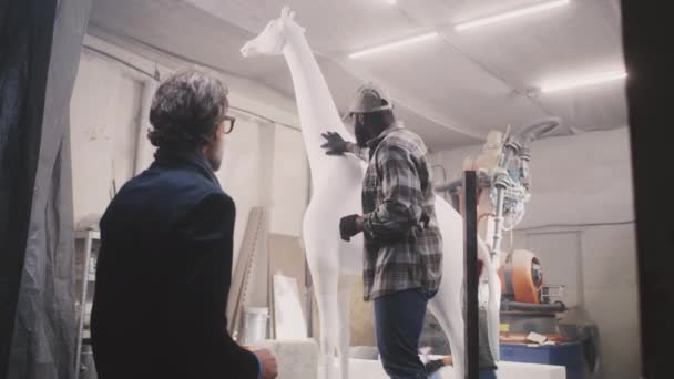 Различные мужчины обсуждают скульптуру жирафа — стоковое видео