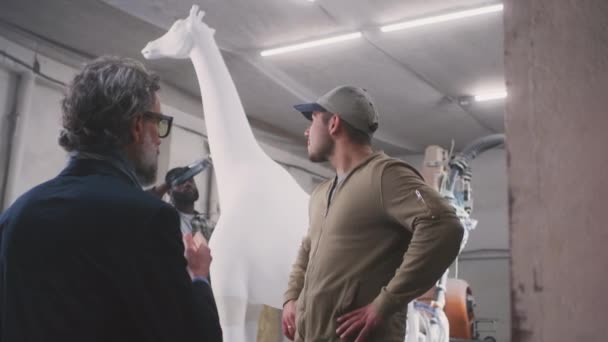 Hommes discutant statue de girafe dans l'atelier — Video