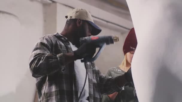 Artesanos multirraciales pintando escultura juntos — Vídeo de stock