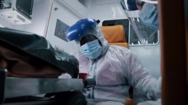 Yorgun siyah sağlık görevlisi tehlikeli madde giysisini çıkarıyor.