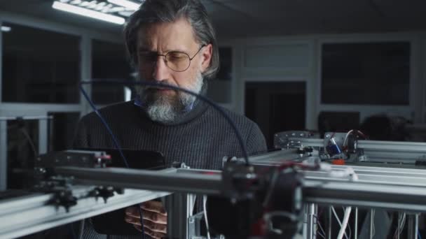 Dojrzały mężczyzna kontrolujący drukarkę 3D — Wideo stockowe