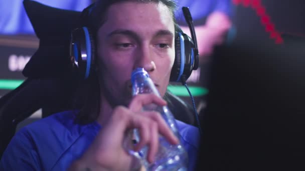 Young gamer with bottle watching replay during tournament — Stock Video